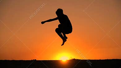 Silhouette of boy jumping against sunset