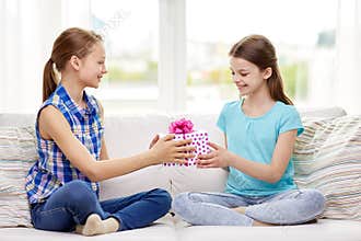 Happy little girls with birthday present at home