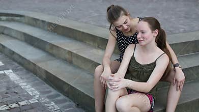 Two young girls sitting on the stone steps, spend time talking.