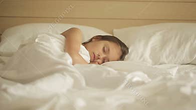 Adorable little girl sleeping in a bed. Dolly shot right to left