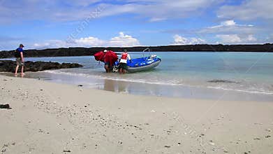 Crew member unloading life vests from the dinghy at Chinese Hat island, Galapagos National Park, Ecuador