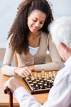 Young carer playing chess with older man