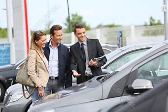 Car dealer showing car to clients