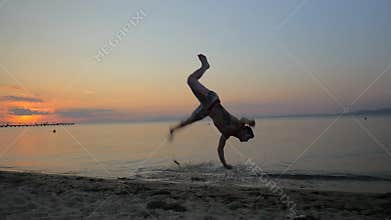 Man showing acrobatics at seaside during sunset