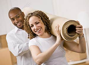 Couple moving into new home carrying rug