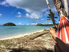 Relaxing under coconut trees shade on colourful hammock