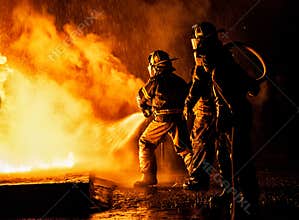 Two firefighters fighting fire with a hose and water