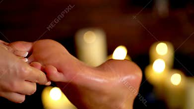 Foot massage therapy on candle burning background. 4k.