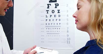 Optometrist discussing eye test report of female patient