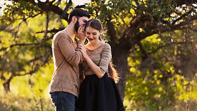 Male from says something in the ear of his girlfriend