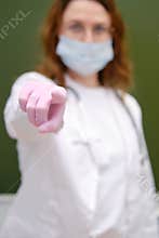 School nurse in a medical mask points her index finger at you. School quarantine education concept