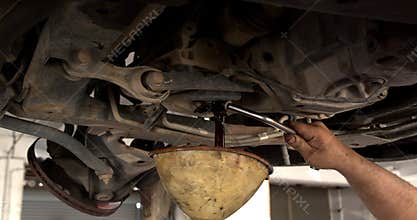 Car mechanic unscrews with a star wrench for repair under the vehicle