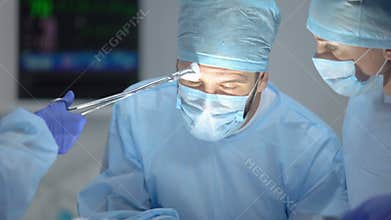 Assistant wiping main surgeon forehead during hospital operation, profession