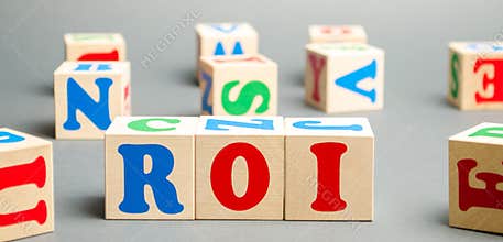 Wooden blocks with the word ROI. Ratio between the net profit and cost of investment resulting from an investment of resources.