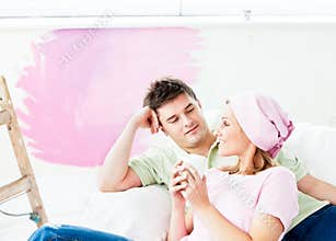 Resting couple lying on sofa after painting a room