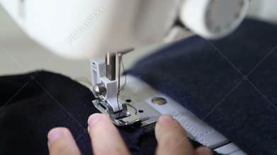 Woman stitching fabric on sewing machine. Close-up of woman`s hand and fabric on sewing machine
