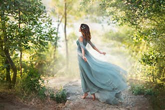 Fairy-tale princess in light summer blue turquoise dress on wide path