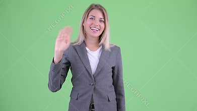 Happy young beautiful blonde businesswoman waving hand