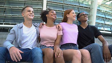 Multi-racial group young people hugging sitting outdoors friendship togetherness