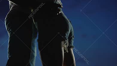 Girl in jeans shorts hugging boyfriend against night sky, adolescent secret love