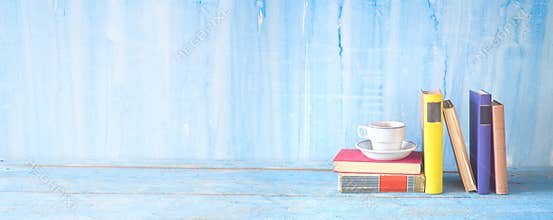 Stack of multicolored hardback books with a cup of coffee, reading education, literature, panoramic, good copy space