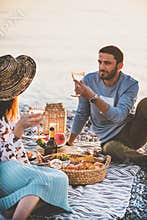 Young couple having picnic with sparkling wine and fruit