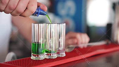 The bartender makes a shot of three alcohol cocktails.