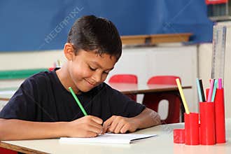 Young school boy 10 writing at his classroom desk
