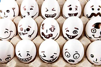 Eggs with drawn cartoon faces in tray.