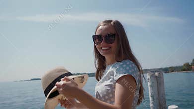 Beautiful girl in sunglasses takes off her straw hat and covers camera with her