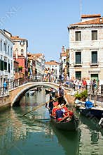 Venice, Italy - JUL 01, 2018: Tourists on old bridge and gondola are taking selfies by mobile phones