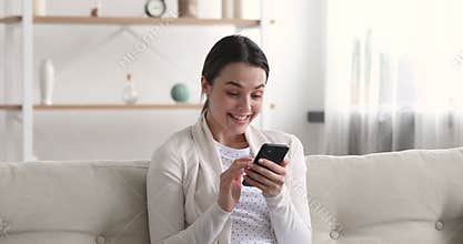 Euphoric young woman celebrating winning bid looking at smartphone