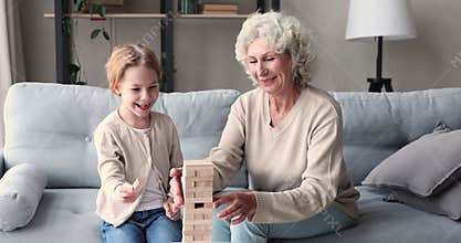 Smart little preschool kid girl playing build with grandmother.
