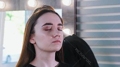 Brow master applying yellow wax on the brow bone of young woman
