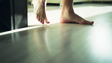 Bare male legs are walking on a bright floor, camera movement, tracking movement