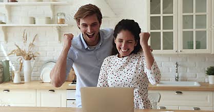 Couple read message on laptop celebrate online lottery success