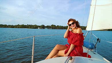 Lovely girl in red dress and sunglasses enjoying adventure on sailing boat