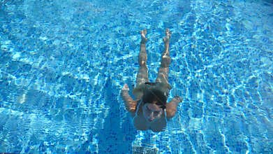 Woman swim under the water and emerges on the surface. Young beautiful girl swimming in pool. Summer vacation or holiday