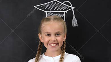 Schoolgirl with square academic cap painted above head smiling at camera