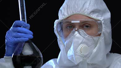 Lady chemist in uniform holding dangerous substance in flask, illegal laboratory
