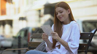 Happy teenage girl admiring photo of boyfriend, secretly kissing it, affection