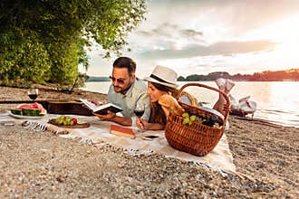 Happy young couple relaxing on a beach, lying on a picnic blanket