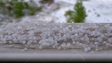 Hail Outside the Window. Pieces of hail lie on the windowsill behind a plastic window.