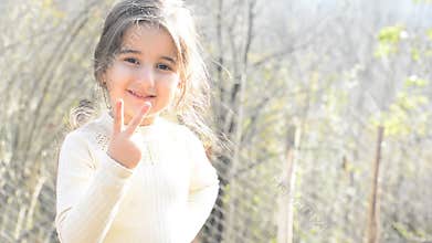Close up portrait of a happy little girl looking directly to camera and counting numbers by right hand