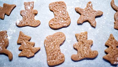Gingerbread cookies on parchment before baking: star, bear, christmas tree and santa boot. Preparations of raw dough in xmas time