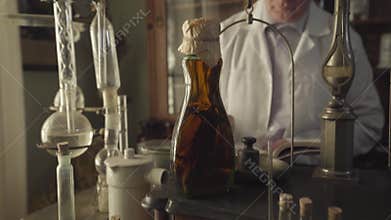 Camera moving up showing old Caucasian apothecary writing with feather pen. Professional working in ancient drugstore