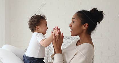 Funny infant baby playing patty cake with african mom