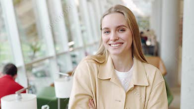 Happy blonde teen girl student standing in university campus. Portrait