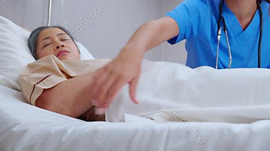 Caregiver care elderly patient while cover blanket on bed at hospital ward, nurse care senior while asleep.