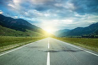 Road in summer mountains to the sunset